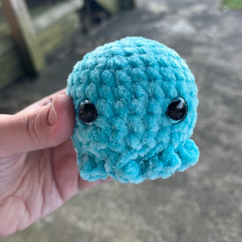 Crocheted blue baby octopus plush stuffed animal with sparkly pink eyes